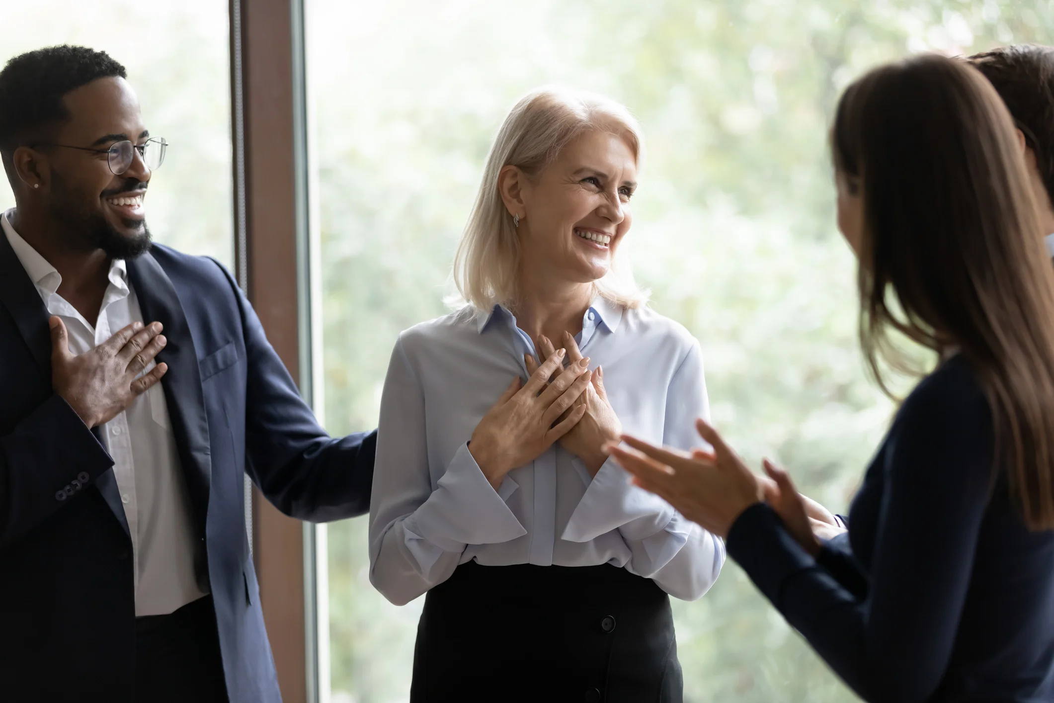 Middle aged businesswoman get congrats and compliments from multiethnic colleagues